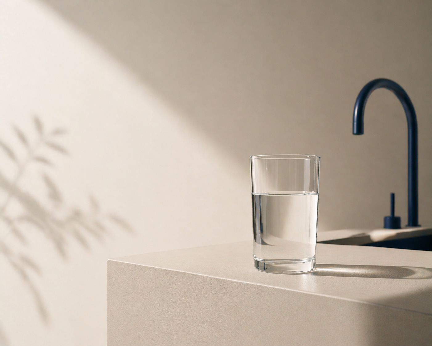 Glas mit Trinkwasser neben einer dunkelblauen Armatur